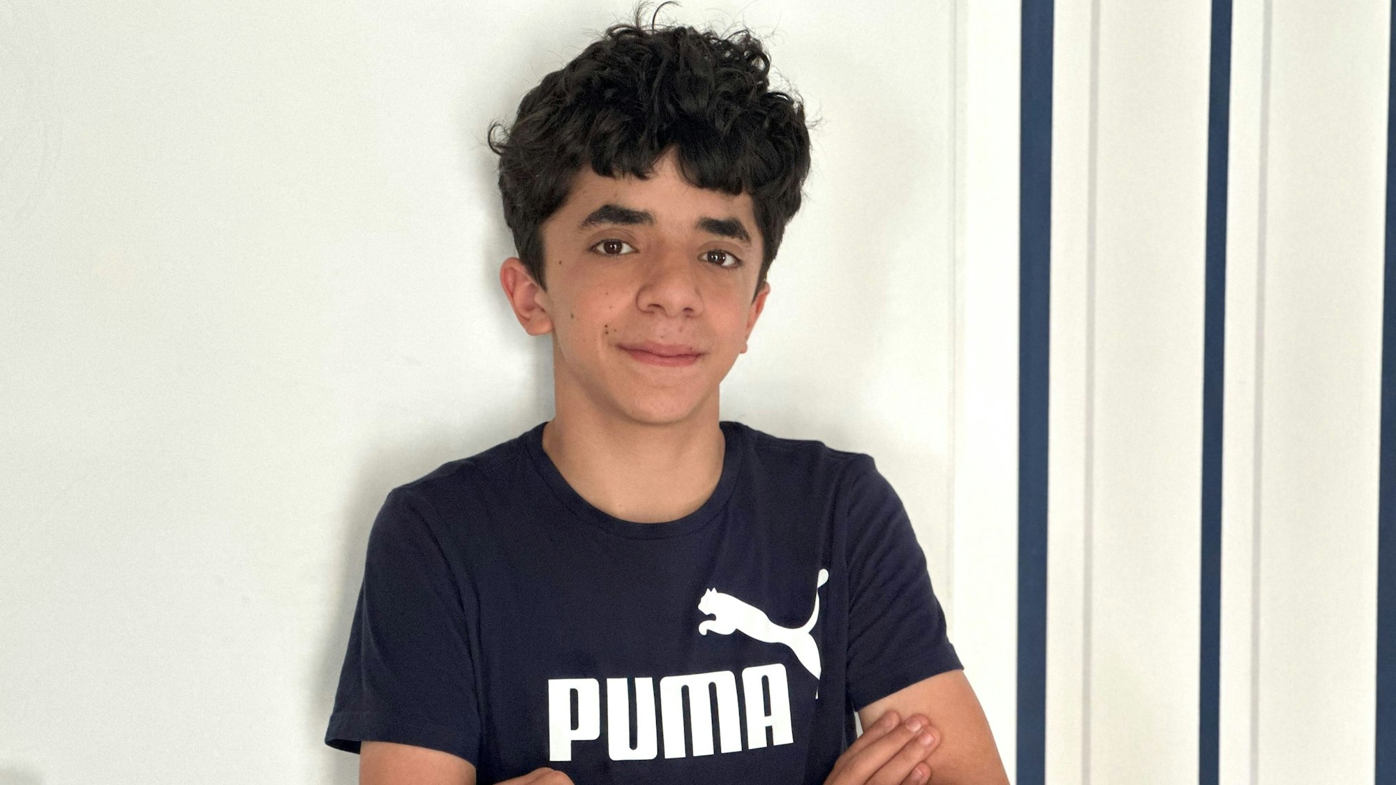 Ein Junge steht vor einer Wand.