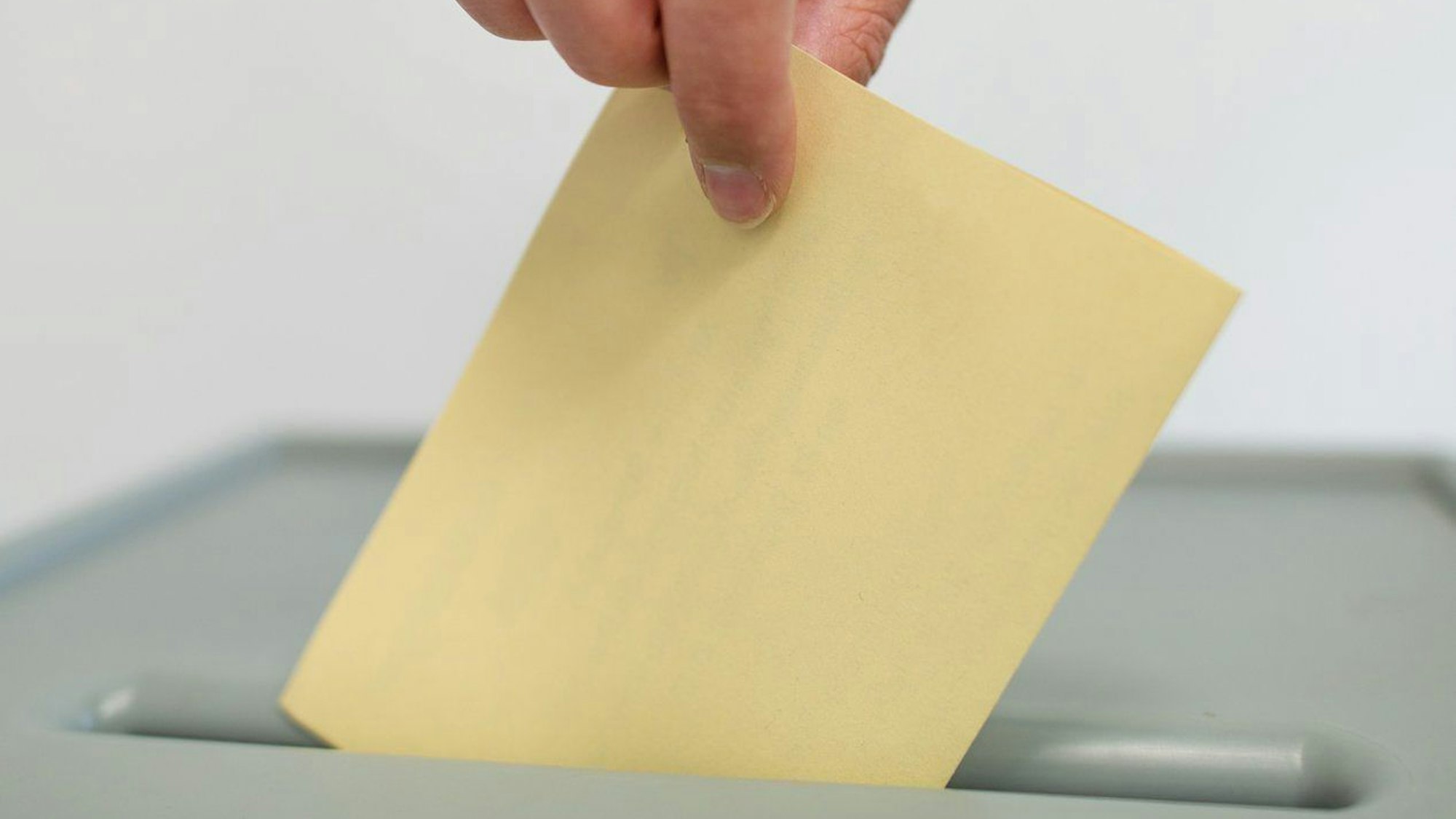 Ein Stimmzettel für den einen Bürgerentscheid wird in eine Wahlurne geworfen.