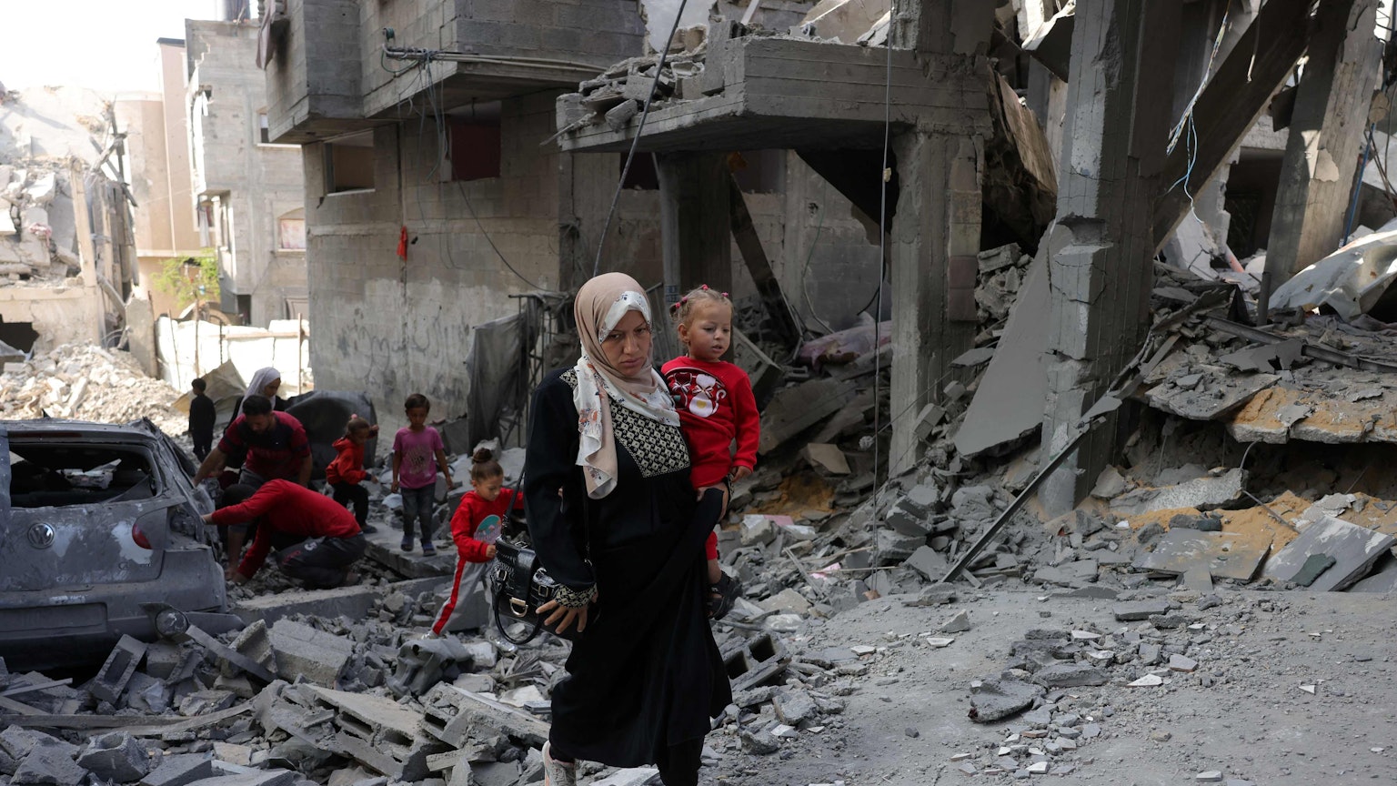 Eine Palästinenserin trägt ein kleines Kind auf dem Arm.