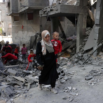 Eine Palästinenserin trägt ein kleines Kind auf dem Arm.