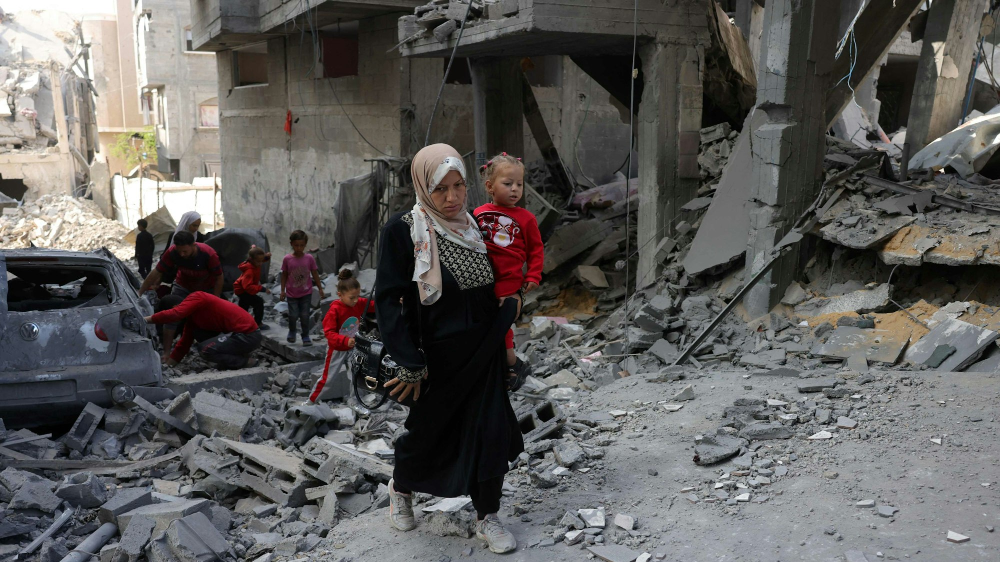 Eine Palästinenserin trägt ein kleines Kind auf dem Arm.