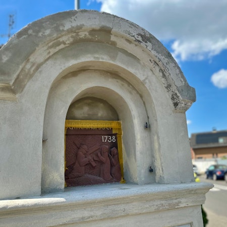 Zu sehen ist ein Bilderstock an einer Straße vor blauem Himmel.