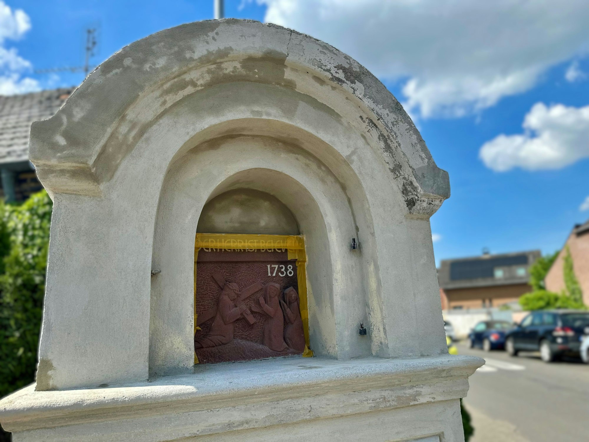 Zu sehen ist ein Bilderstock an einer Straße vor blauem Himmel.