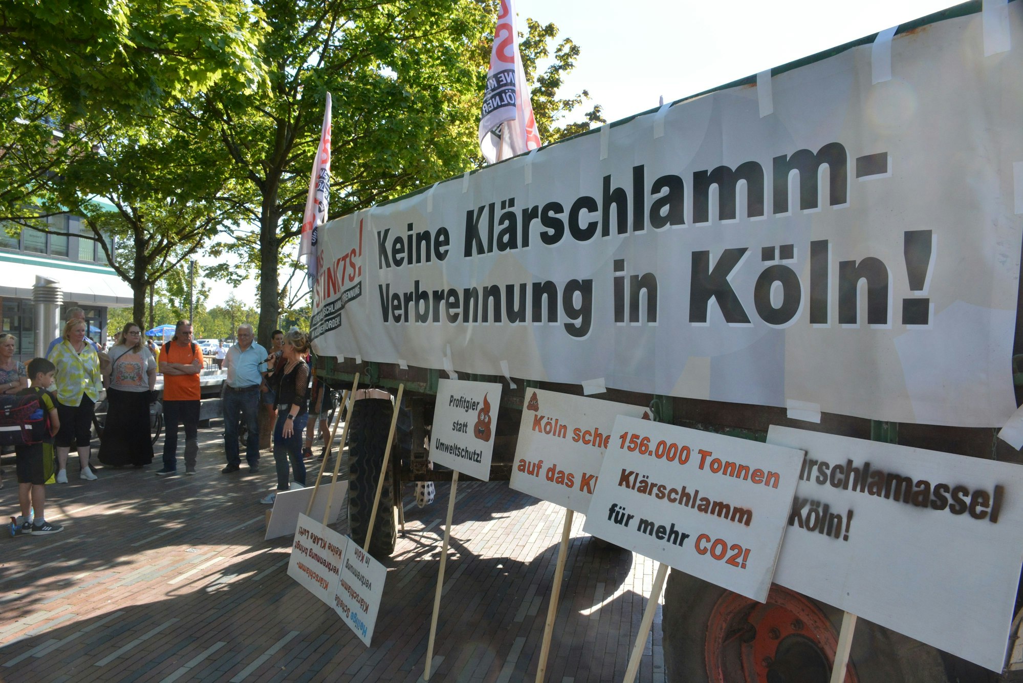 Transparente gegen den Klärschlamm und einige Menschen sind zu sehen.