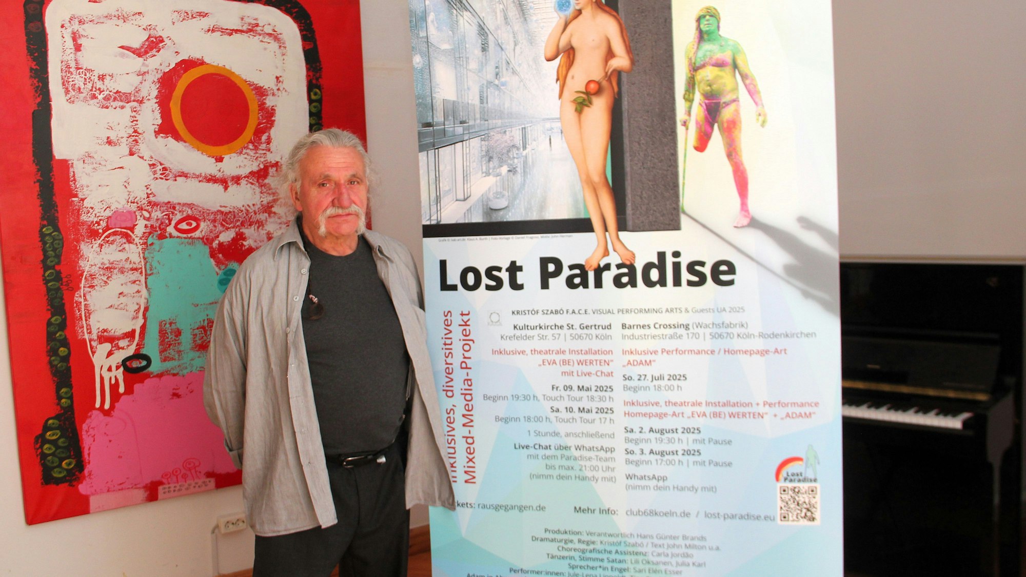 Ein Mann mit grauem Haar und Bart steht zwischen zwei Aufstellern.