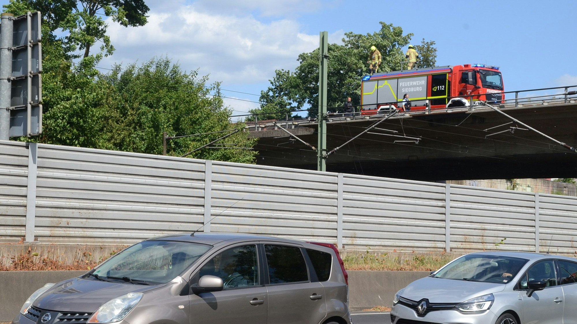 Feuerwehrleute kontrollieren den Bereich an der Bahntrasse von der Umgehungsstraße aus.