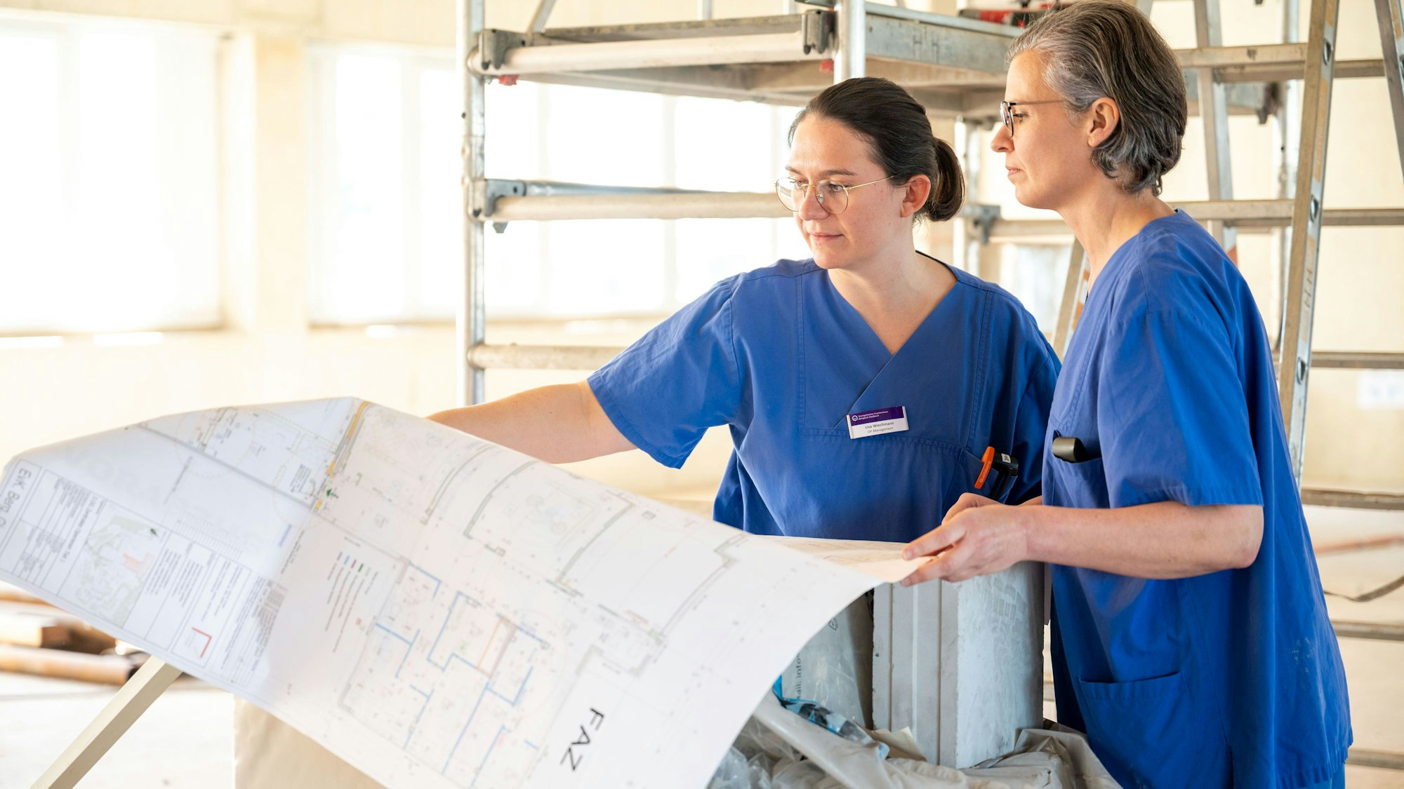 Zwei Mitarbeiterinnen  des EVK haben die Baupläne für das geplante OP-Zentrum in den Händen.