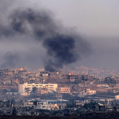 Rauch über zerstörten Gebäuden im Gazastreifen: Israel bombardiert erneut das Küstengebiet – rund 90 UN-Hilfstransporte sind unterwegs.