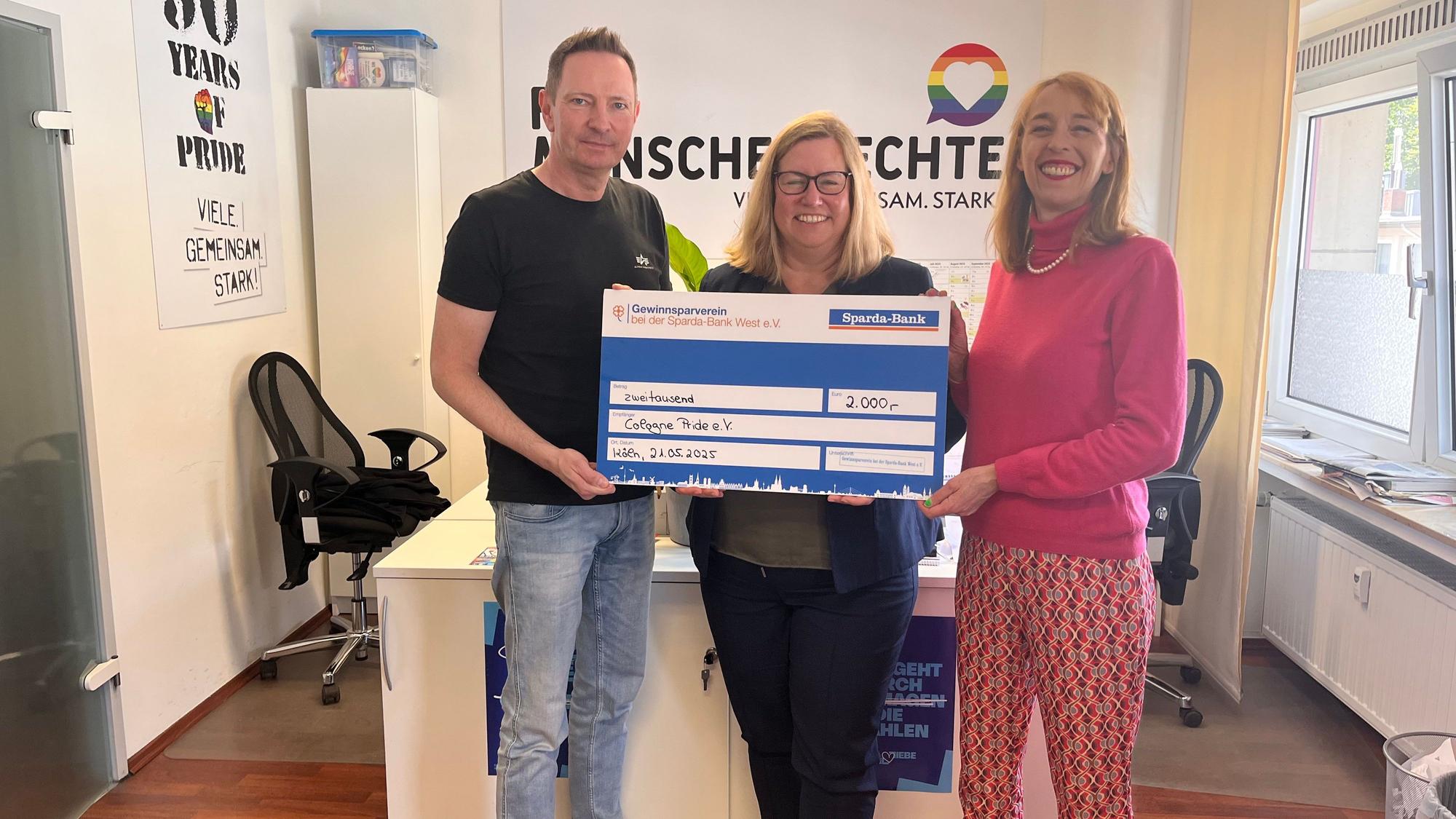 Tanja Decking (m.) Generalbevollmächtigte der Sparda Bank West überreicht Natalie Hagen (r.) und Uwe Weiler (l.) vom Cologne Pride e.V. den Scheck über 2000 Euro im Büro der Vereins.