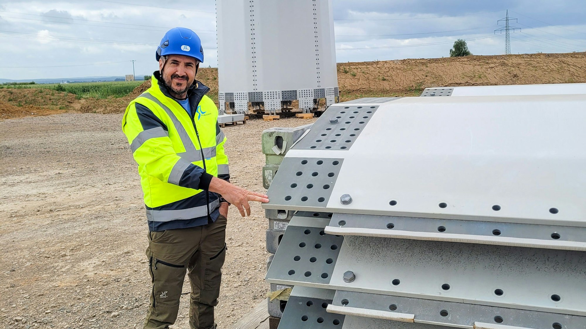 Das Bild zeigt den Bauleiter. Er trägt eine gelbe Weste und einen blauen Helm.