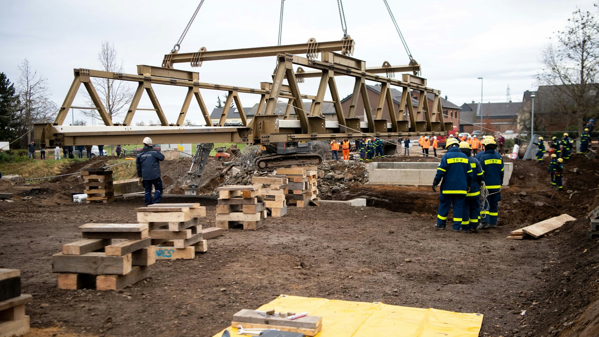 Ein Kran hievt die Brücke unter den Augen von THW-Einsatzkräften an ihren Platz.