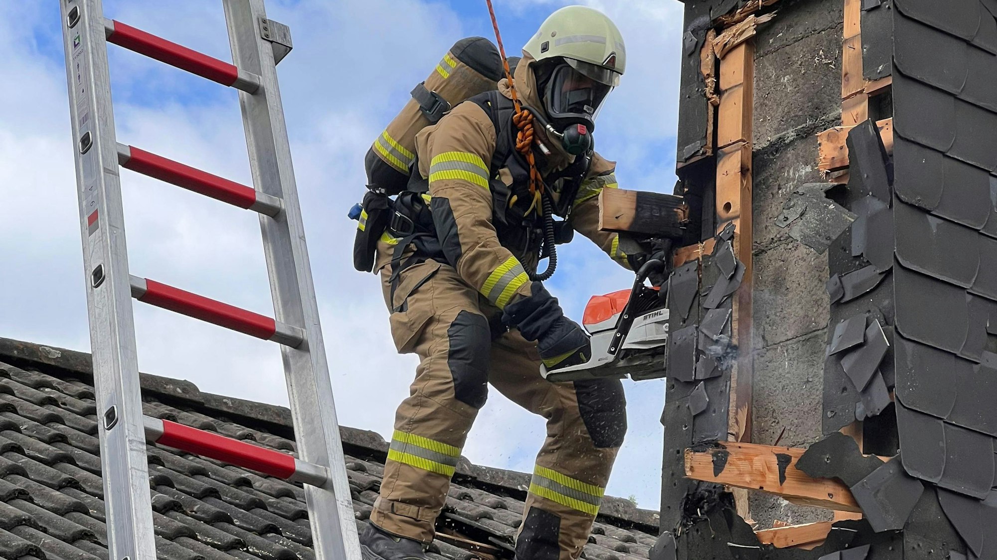 Ein Feuerwehrmann öffnet einen Kamin mit einer Motorsäge.