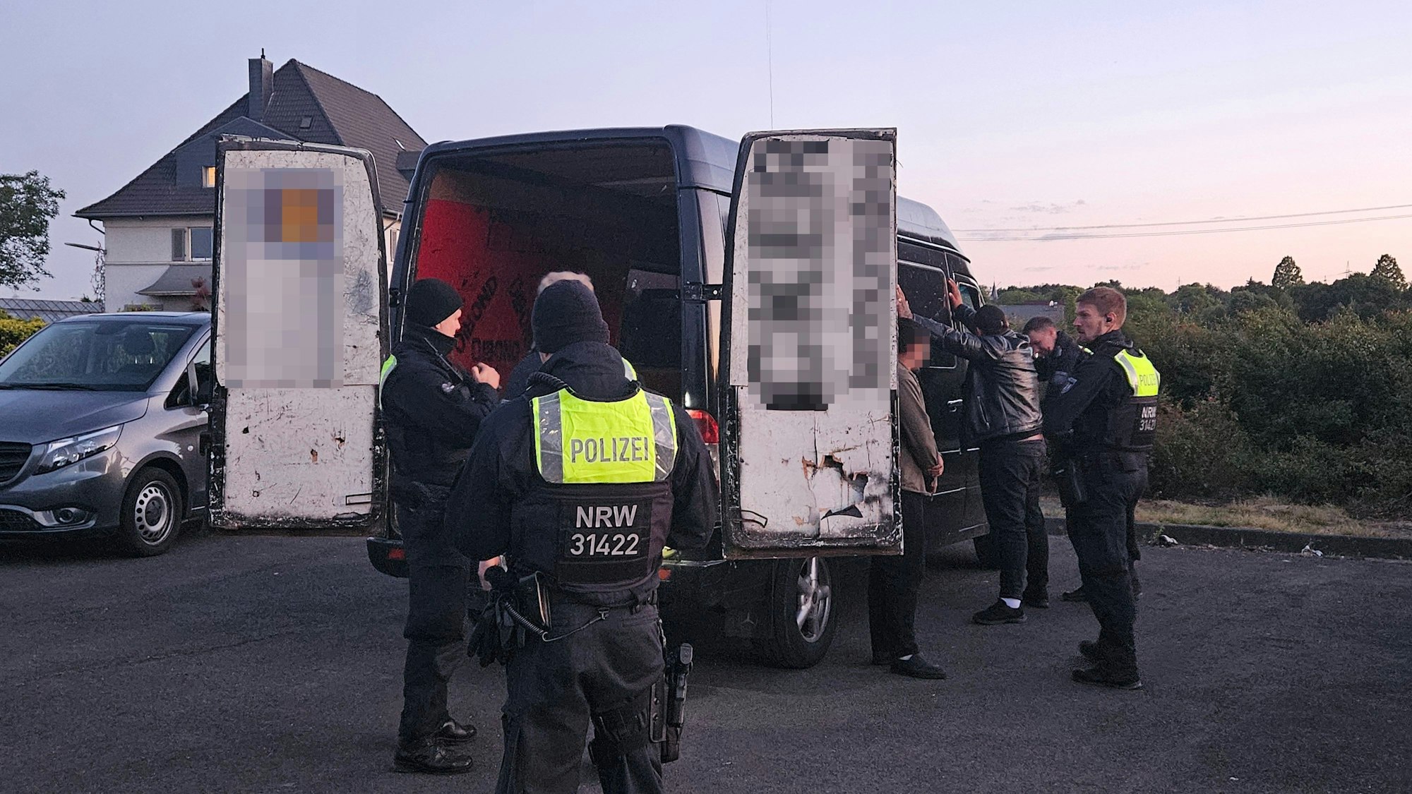 Zu sehen sind Polizisten, die einen Lieferwagen in Augenschein nehmen.