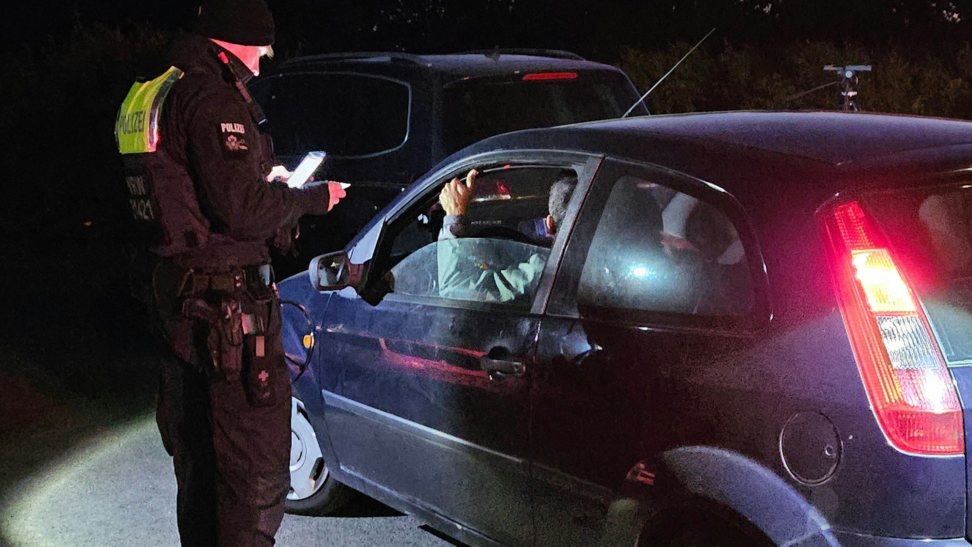 Zu sehen ist ein Polizist, der einen Autofahrer kontrolliert.