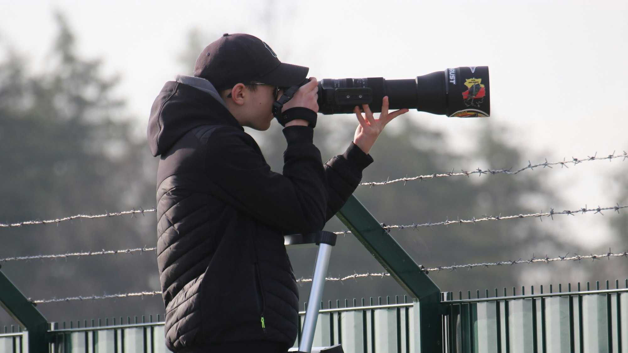 Das Foto zeigt einen jungen Mann hinter der Kamera mit Teleskop-Objektiv.