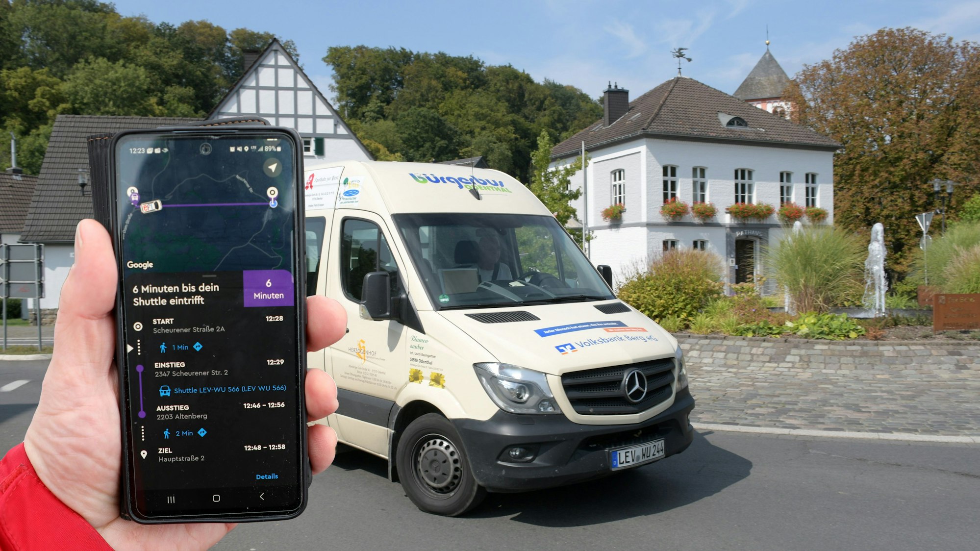 Eine Fotocollage zeigt eine Hand, die ein Handy vor einem Bürgerbus hält.