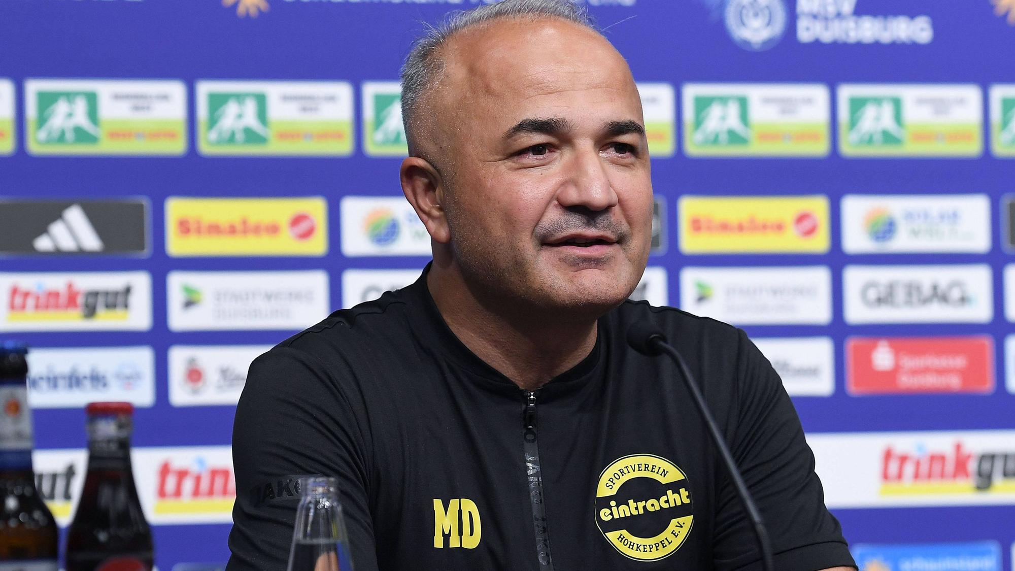 Ein Fußballtrainer spricht in einer Pressekonferenz.
