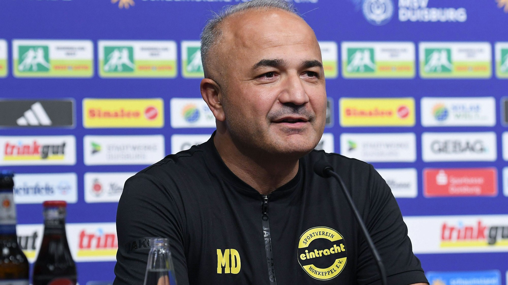 Ein Fußballtrainer spricht in einer Pressekonferenz.