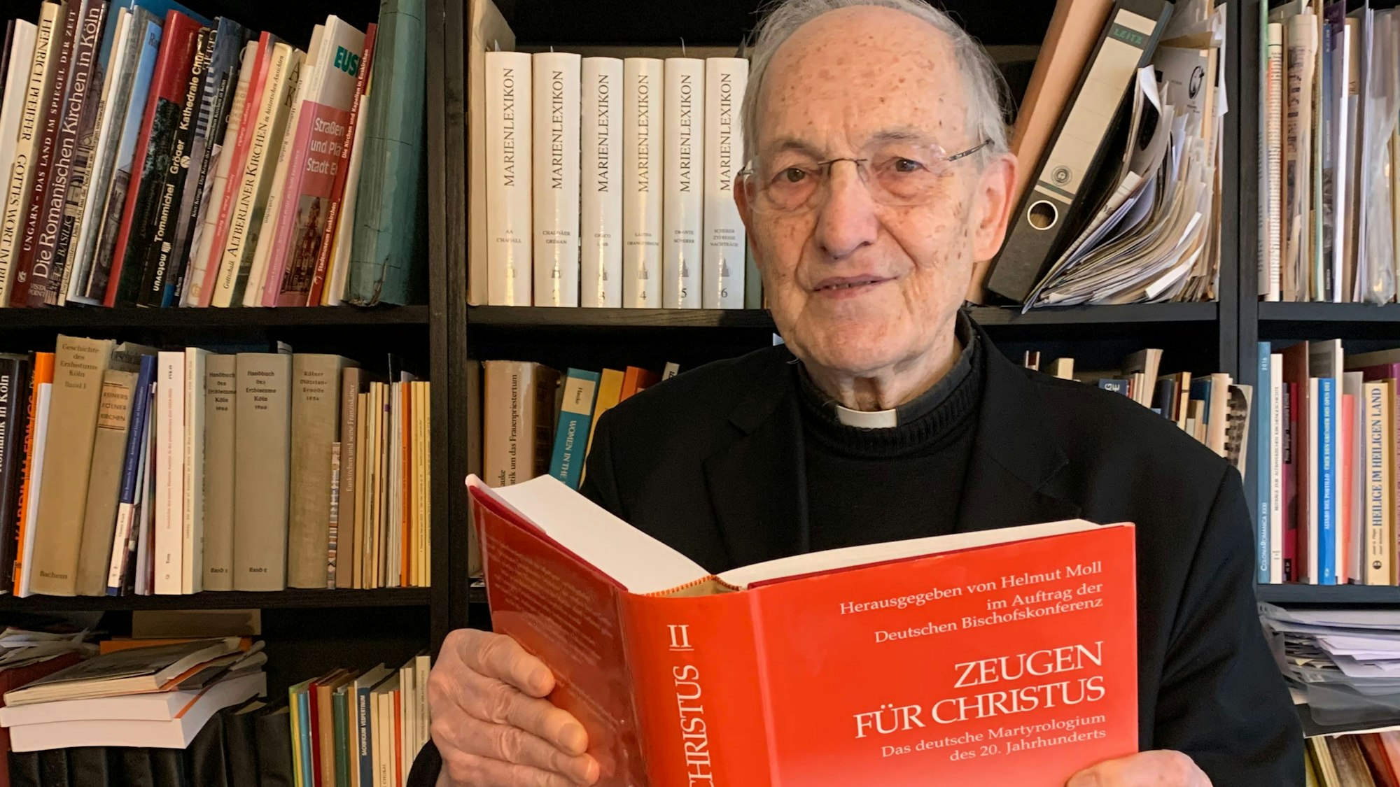 Das Foto zeigt Prälat Helmut Moll mit dem von ihm herausgegeben Werk über katholische Märtyrer.