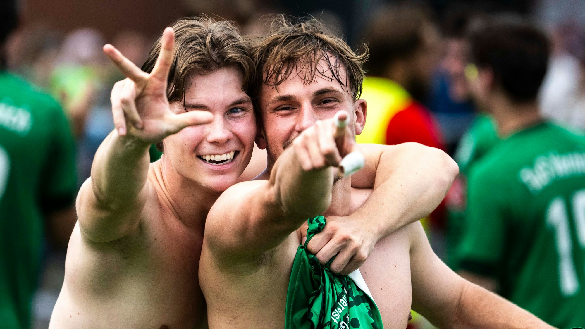 Zwei Vernicher Fußballer mit nacktem Oberkörper jubeln. Einer zeigt mit den Fingern eine Drei ein, der andere zeigt mit einem Finger in die Kamera.