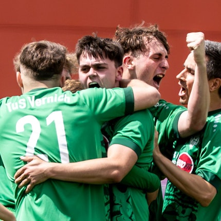 Spieler des TuS Vernich liegen sich jubelnd in den Armen.
