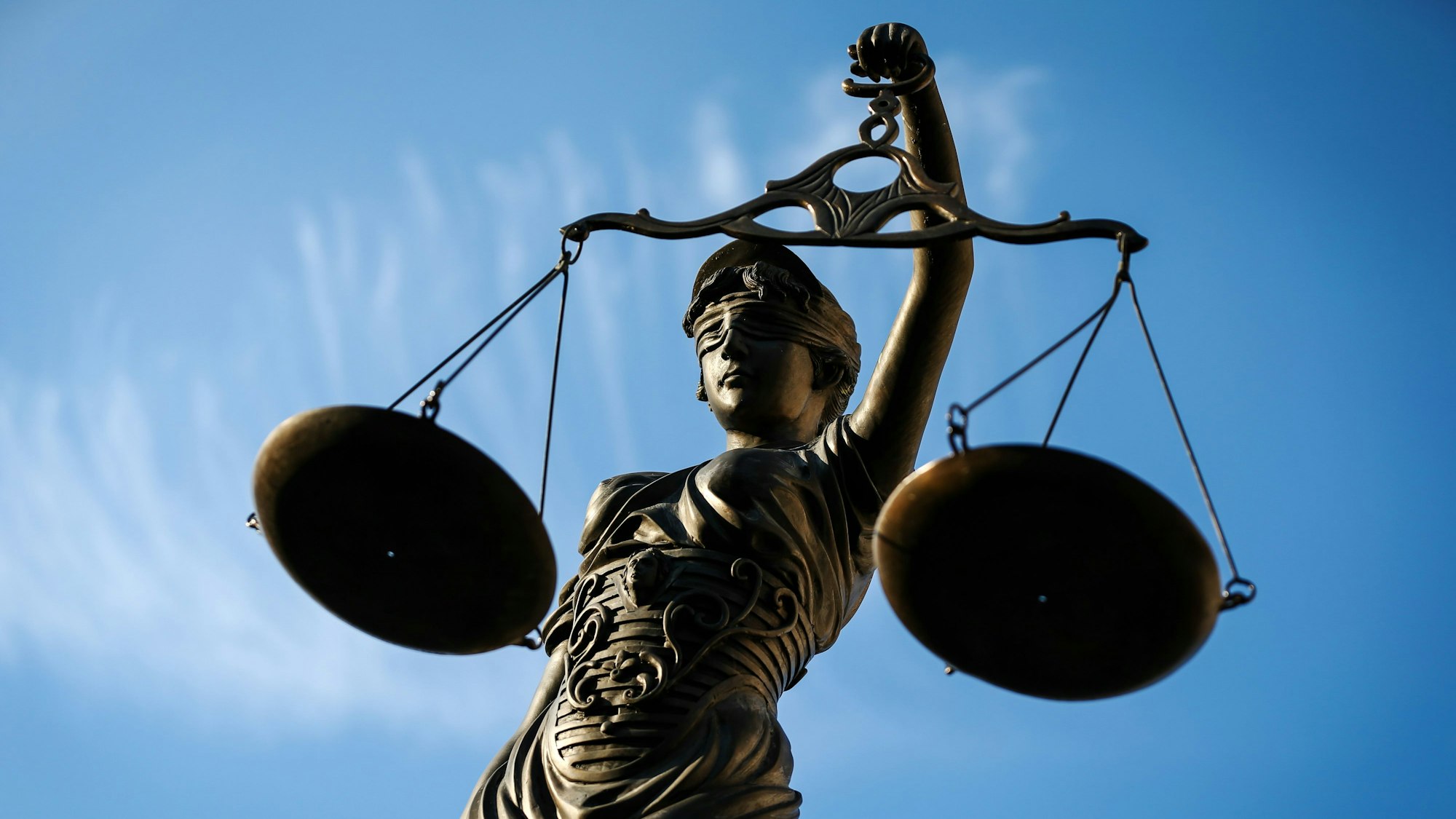 Die Bronzefigur einer Justitia hält zwei Waagschalen in der Hand.