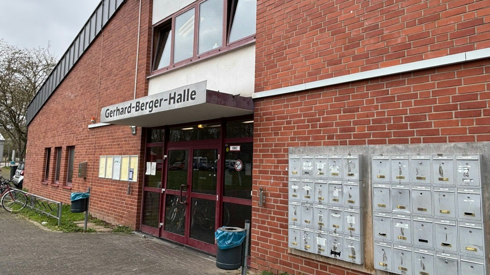 Auf dem Bild ist eine Turnhalle zu sehen. Neben dem Eingang sind Briefkästen für die dort untergebrachten Menschen montiert.