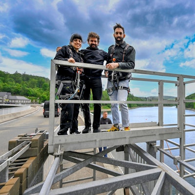 Künstler stehen in einem Hängegerüst.