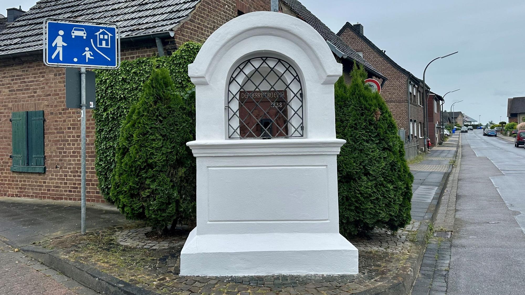 Zu sehen ist ein weißer Bilderstock an einer Straße.