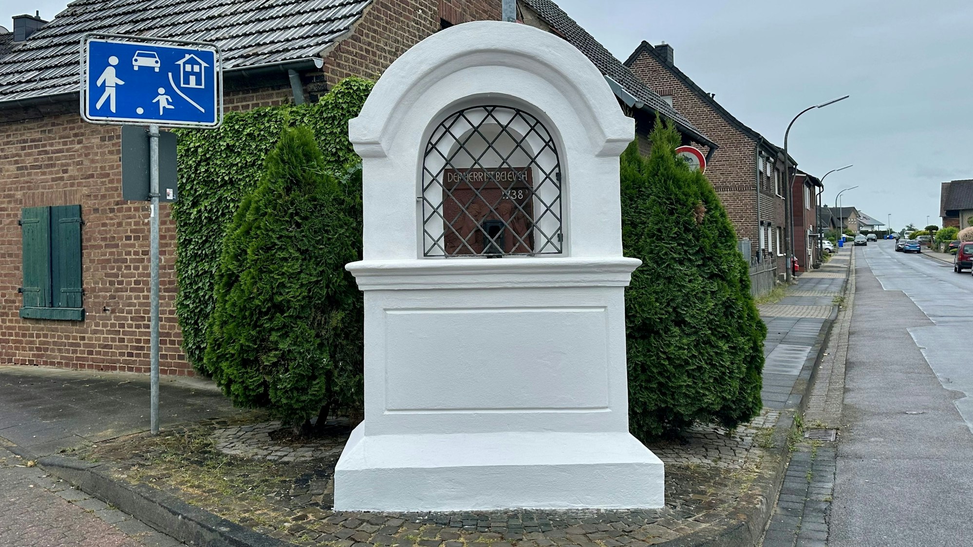 Zu sehen ist ein weißer Bilderstock an einer Straße.