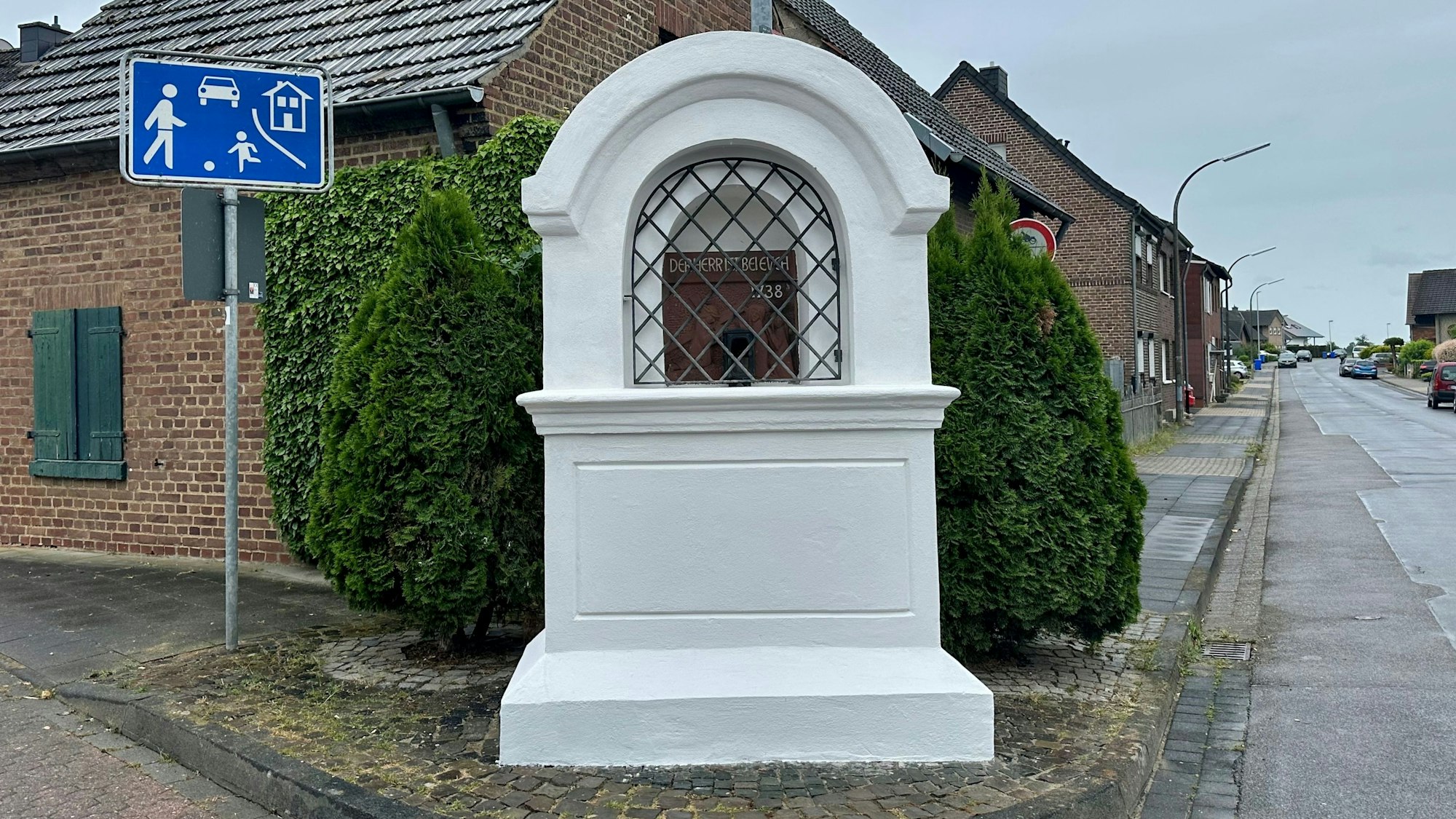 Zu sehen ist ein weißer Bilderstock an einer Straße.