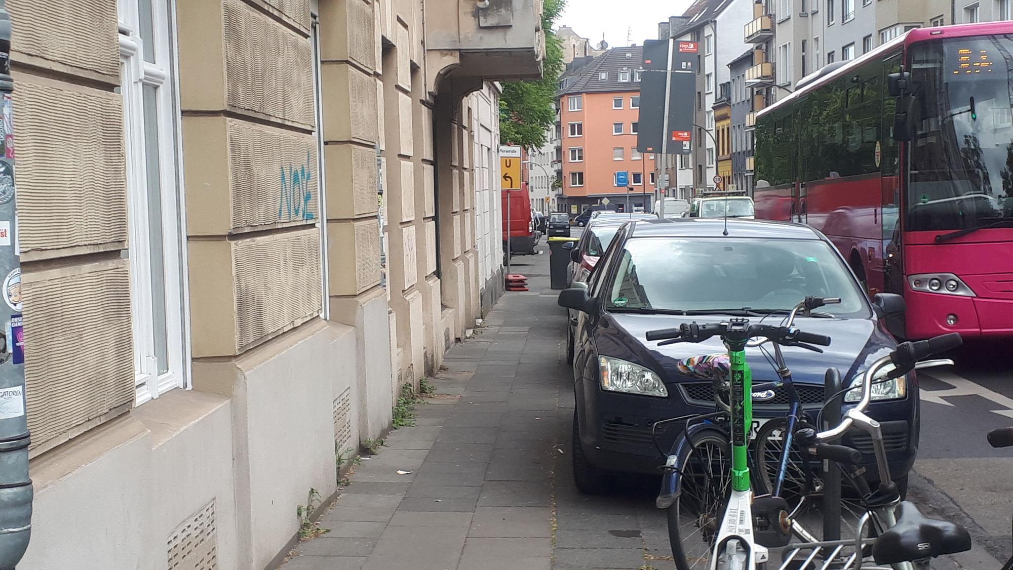 Ein Bürgersteig ist wegen parkender Autos total eng.