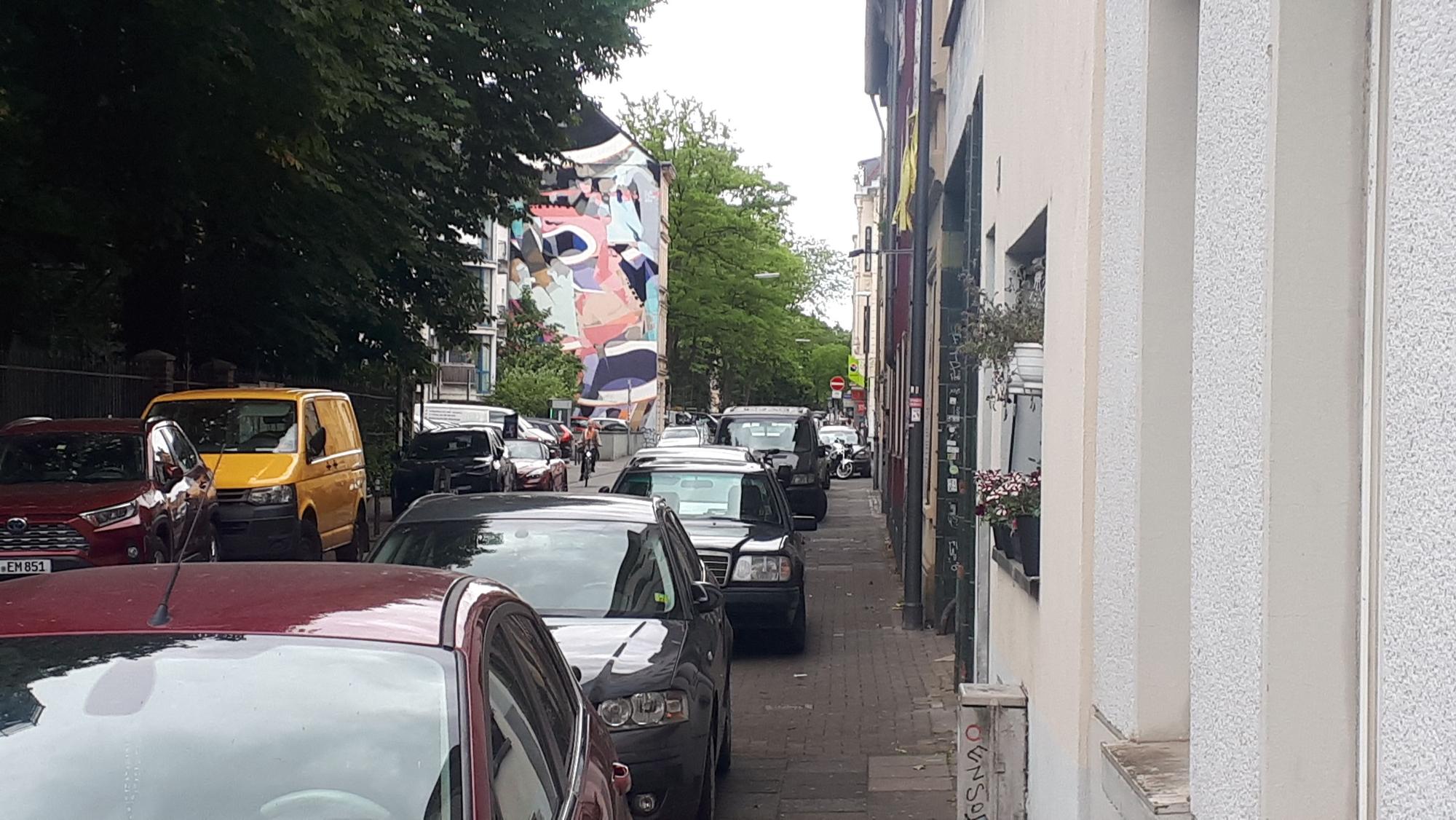 Ein Gehweg ist fast komplett von Autos zugeparkt.