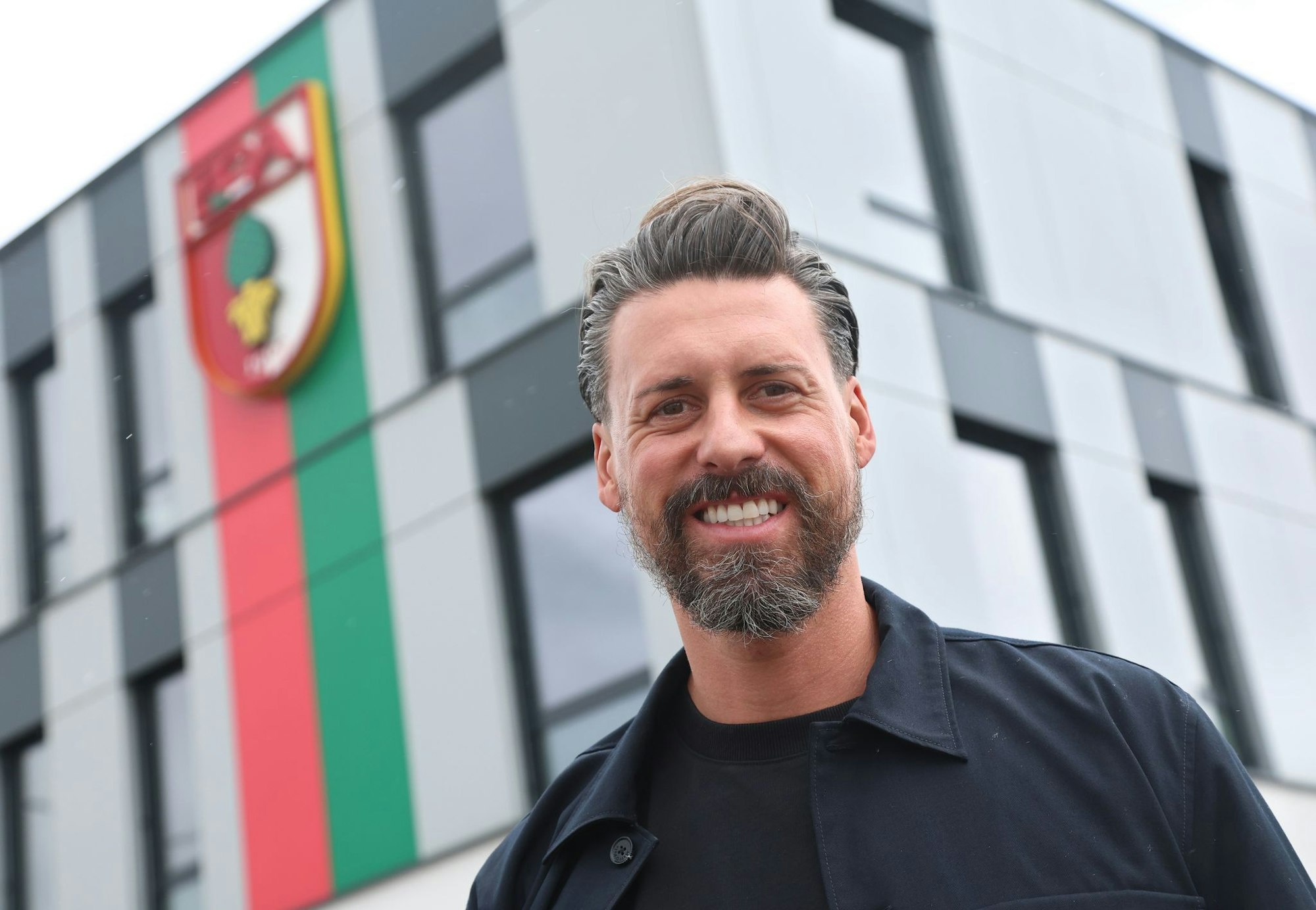 Der neue Trainer Sandro Wagner posiert vor der Geschäftsstelle des FC Augsburg.