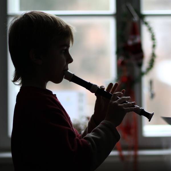 Das Foto zeigt einen Musikschüler, der auf einer Blockflöte spielt.
