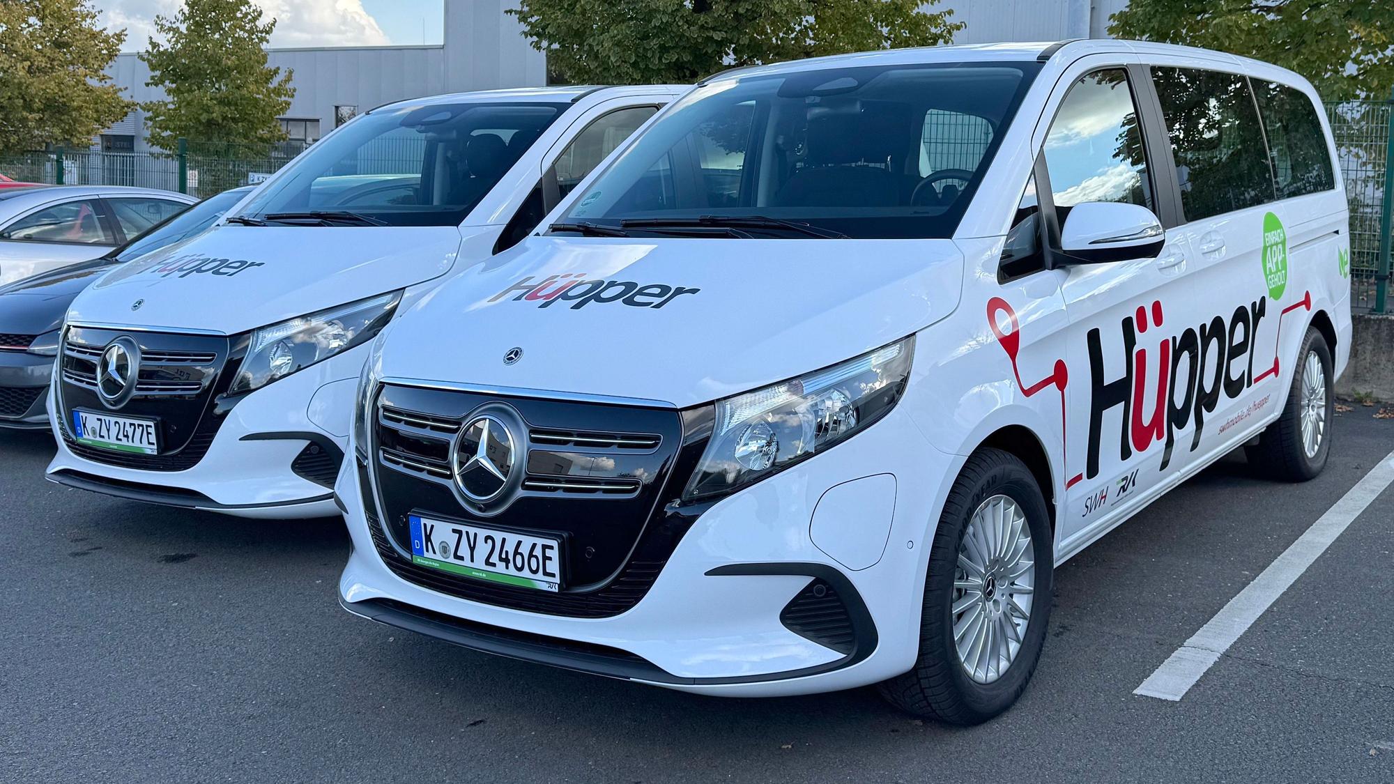 Das Foto zeigt zwei Mercedes-Vans mit dem markanten Hüpper-Logo.