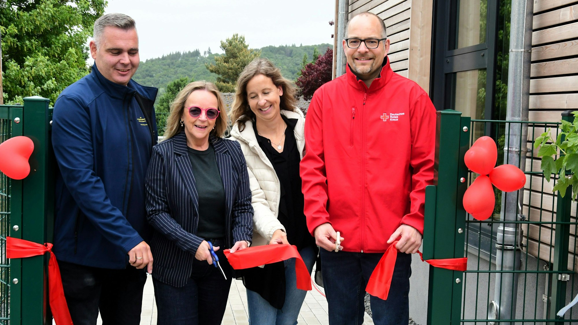 Zwei Männer und zwei Frauen stehen mit Scheren in der Hand an einem roten Band, das durchschnitten wurde.