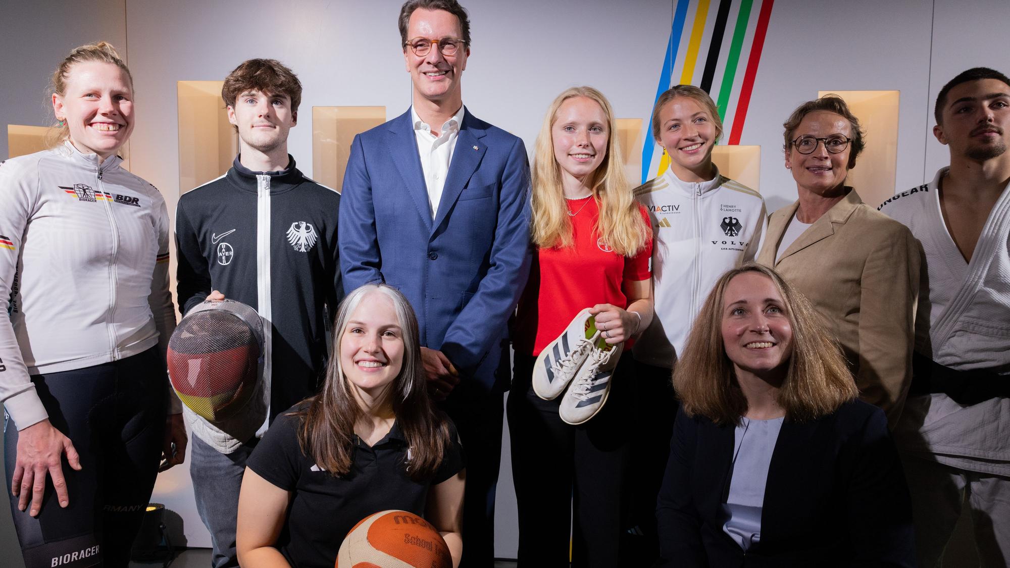 28.05.2025, Nordrhein-Westfalen, Köln: Hendrik Wüst (hinten 3.v.l, CDU), Ministerpräsident von Nordrhein-Westfalen, steht zusammen mit Sportlern und Olympiasiegerin Isabell Werth (hinten 2.v.r) bei der Vorstellung des Konzepts einer Olympia-Bewerbung mit der Rhein-Ruhr-Region für die Olympischen Spiele. Foto: Rolf Vennenbernd/dpa +++ dpa-Bildfunk +++