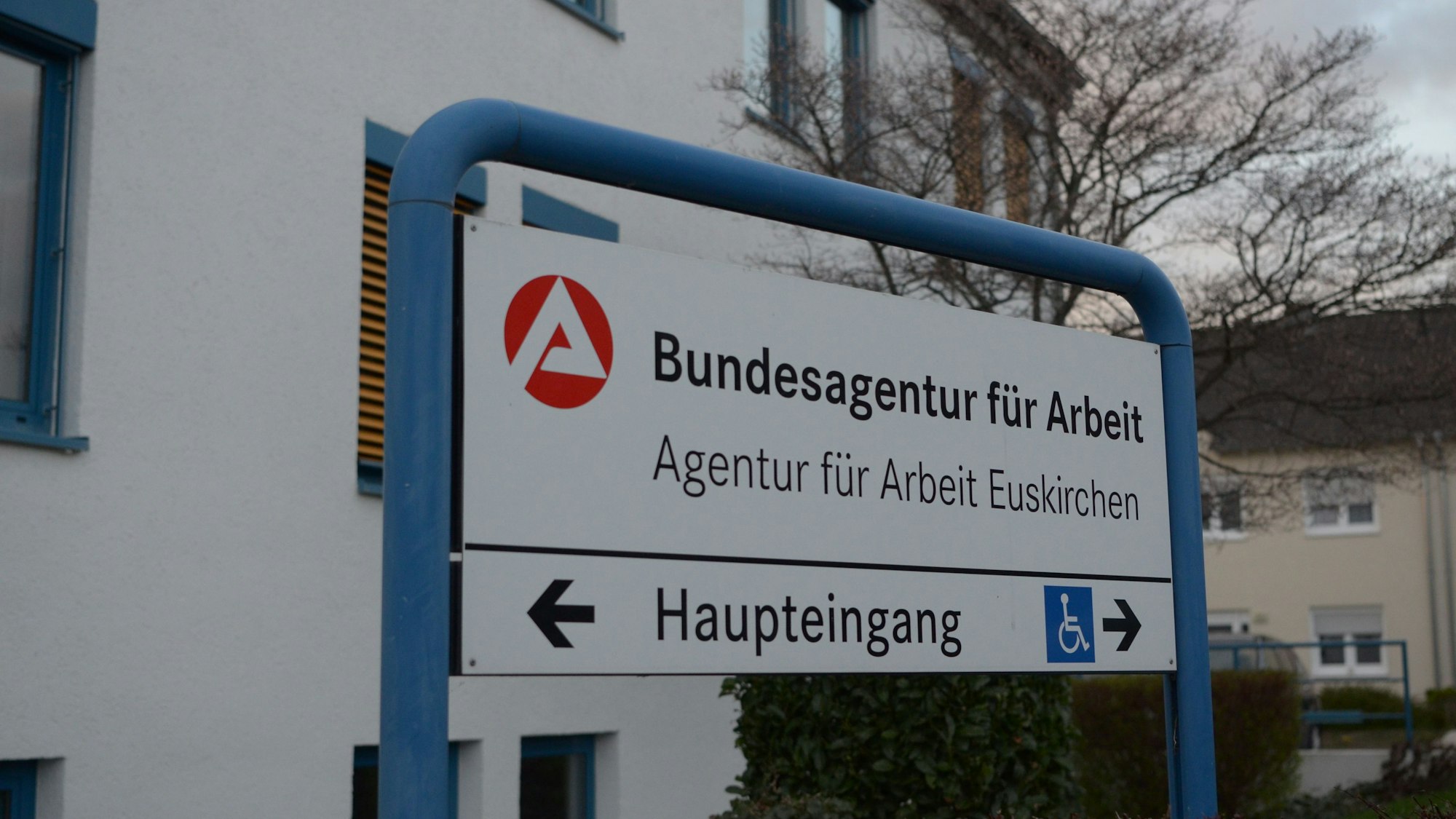 Vor dem Gebäude steht ein Schild mit der Aufschrift „Agentur für Arbeit Euskirchen“.