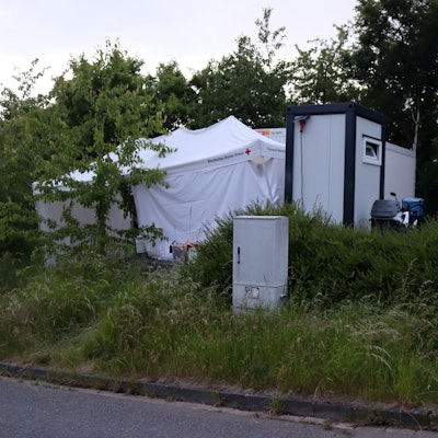 Vor den Wohncontainern der Stadt haben die Ermittler der Bonner Polizei ein weißes Zelt aufgebaut, um Spuren zu sichern.
