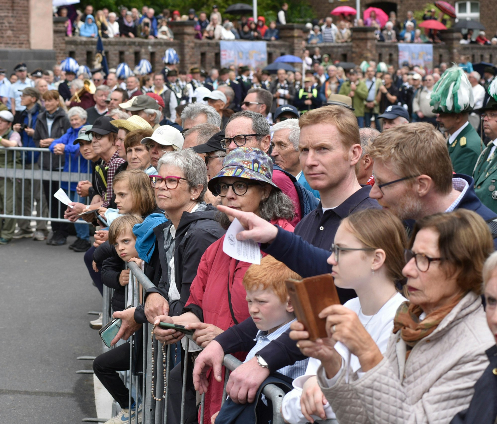 Menschen stehen an einer abgezäunten Straße.