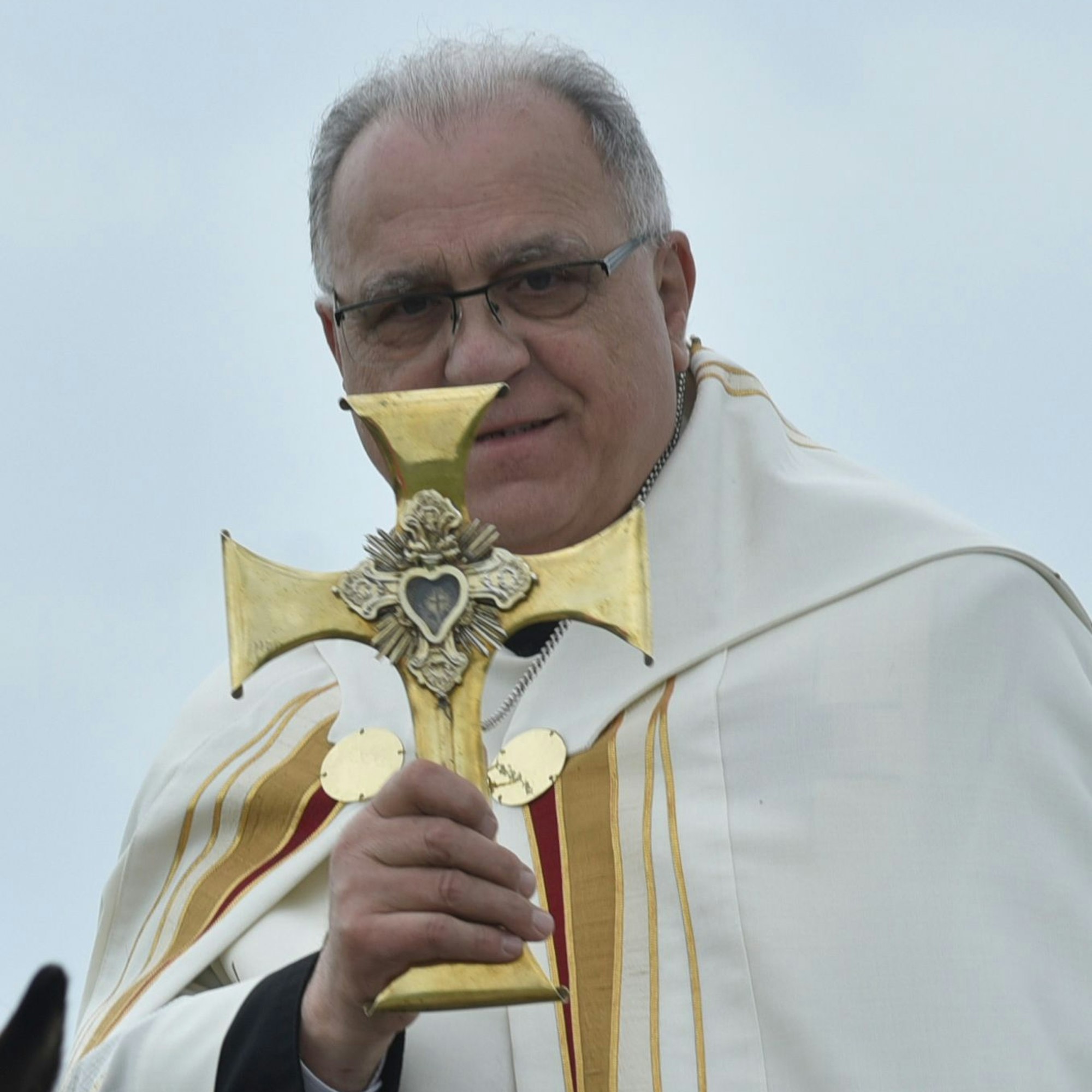 Ein Pfarrer hält ein Kreuz.