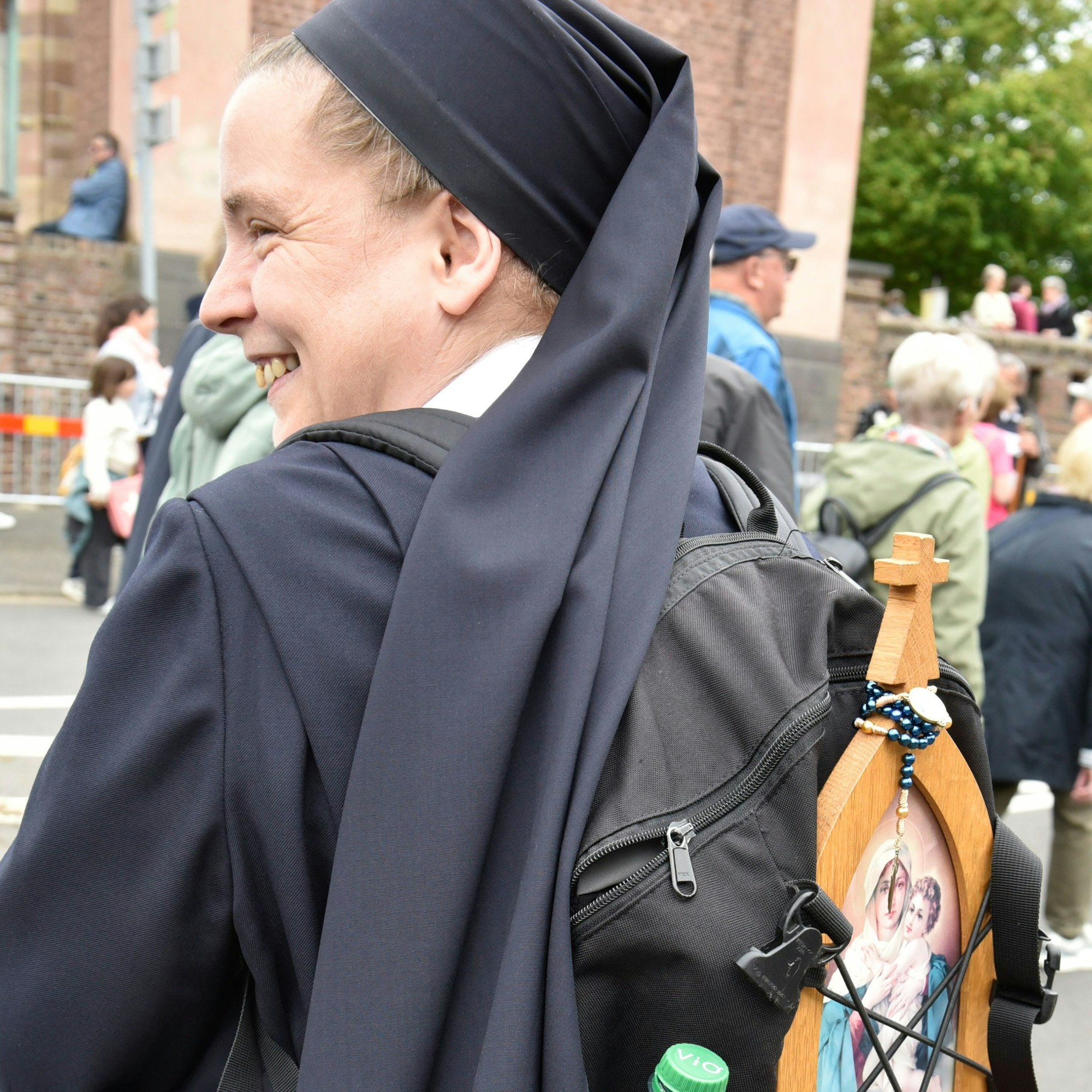 Zu sehen ist eine Schwester mit Rucksack, die lächelt.