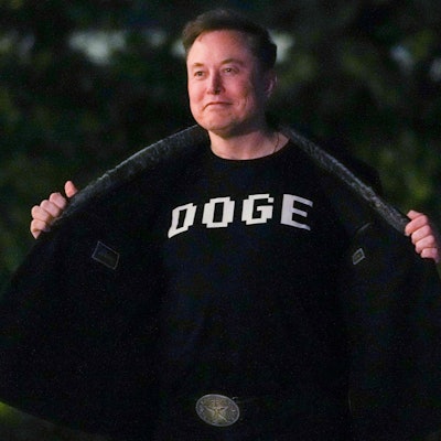 Elon Musk zeigt ein T-Shirt mit der Aufschrift „Doge“.