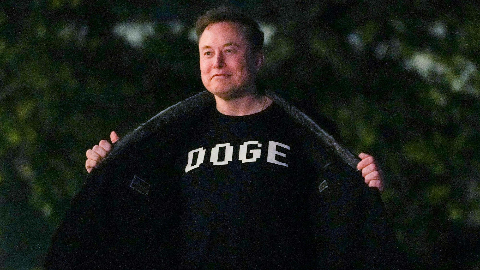 Elon Musk zeigt ein T-Shirt mit der Aufschrift „Doge“.