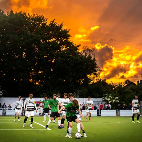 Das Bild zeigt eine Szene eines Fußballspiels. Im Hintergrund geht die Sonne unter.