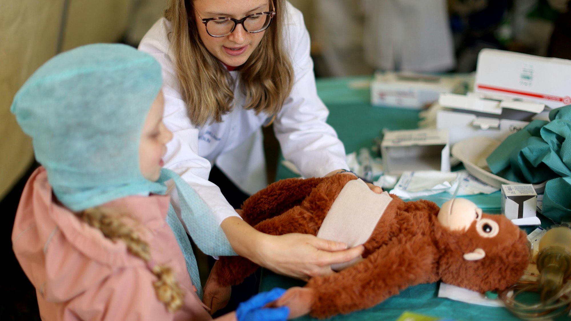 Dieses Äffchen brauch dringend einen Verband. Seine junge Besitzerin schlüpft in die Rolle einer Ärztin und übernimmt die Behandlung. Anleitung bekommt sie durch eine Medizin-Studentin.