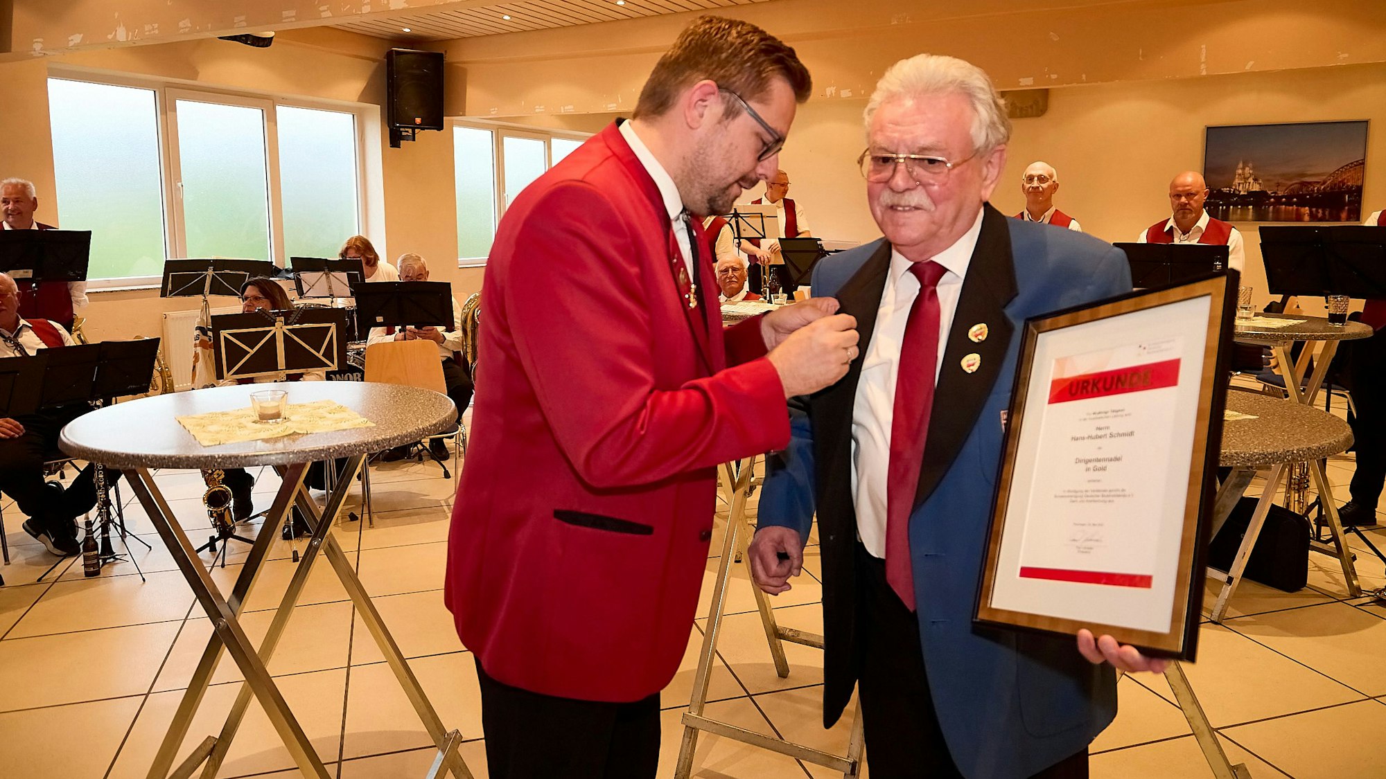 Dirk Eschweiler bereitet die Nadel vor, um sie Hans-Hubert Schmidt anzustecken. Der hält bereits die Urkunde in der Hand.