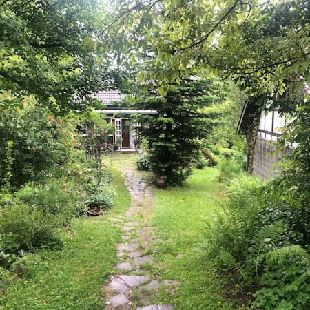 Ein kleines Haus steht am Ende eines kleinen Weges, der durch einen idyllischen Garten führt.