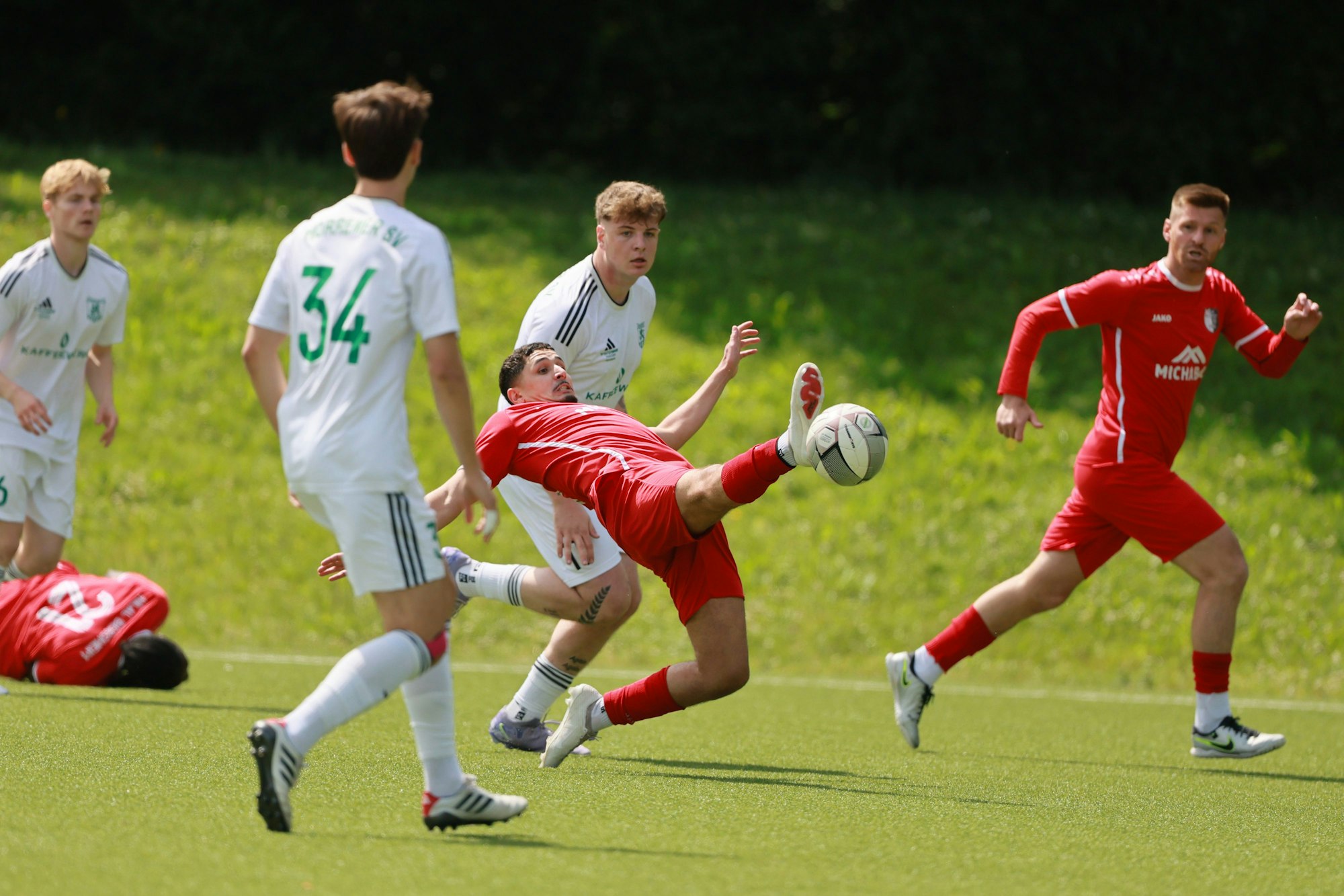Das Foto zeigt den Fußballer Mohamed Bousfia von Hilal-Maroc, der fast waagerecht in die Luft liegt und dabei versucht, an den Ball zu kommen.